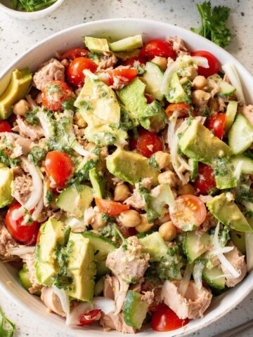 A white bowl with chickpea tuna avocado salad with a honey dijon dressing.