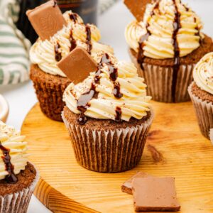 Baileys cupcakes on a wooden cutting board.