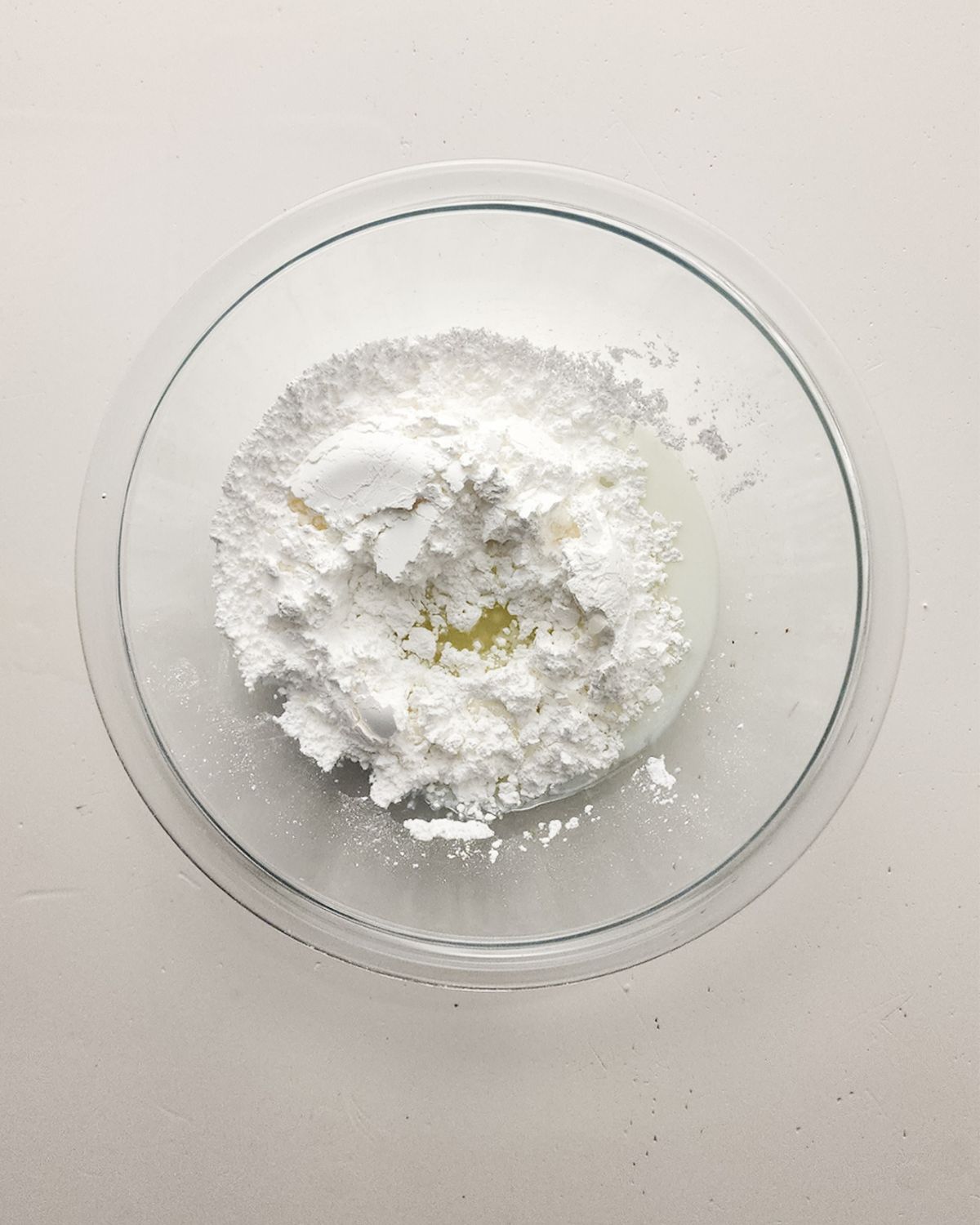 A mixing bowl with confectioners sugar and lemon juice to make a glaze for a lemon poppy seed loaf.
