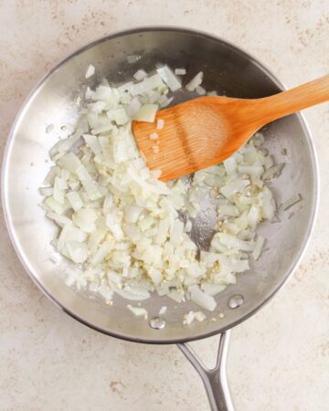 Diced onions being sauteed in a pan to make oven baked beef tacos.