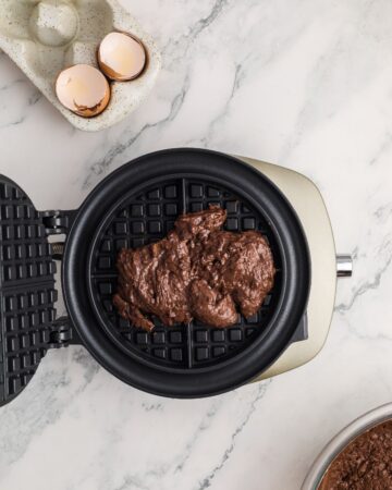 A waffle maker with chocolate waffle ingredients in the waffle maker. 