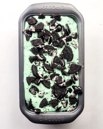 A pan with mint ice cream and chopped oreos to make ice cream. 