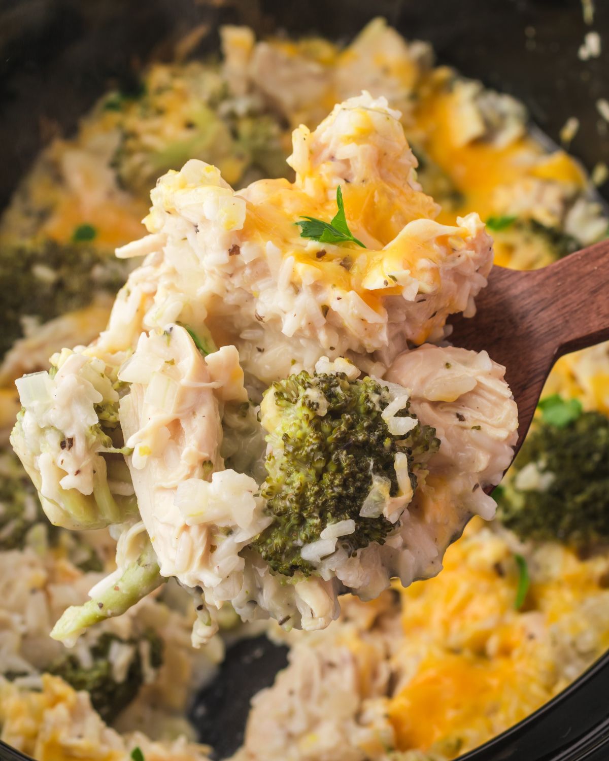 Broccoli, rice, and chicken being picked up with a spoon out of the crockpot.