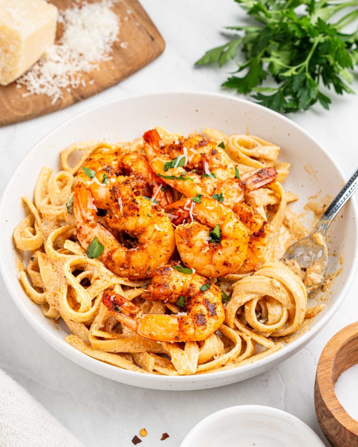 Cajun shrimp over pasta in a large white bowl.