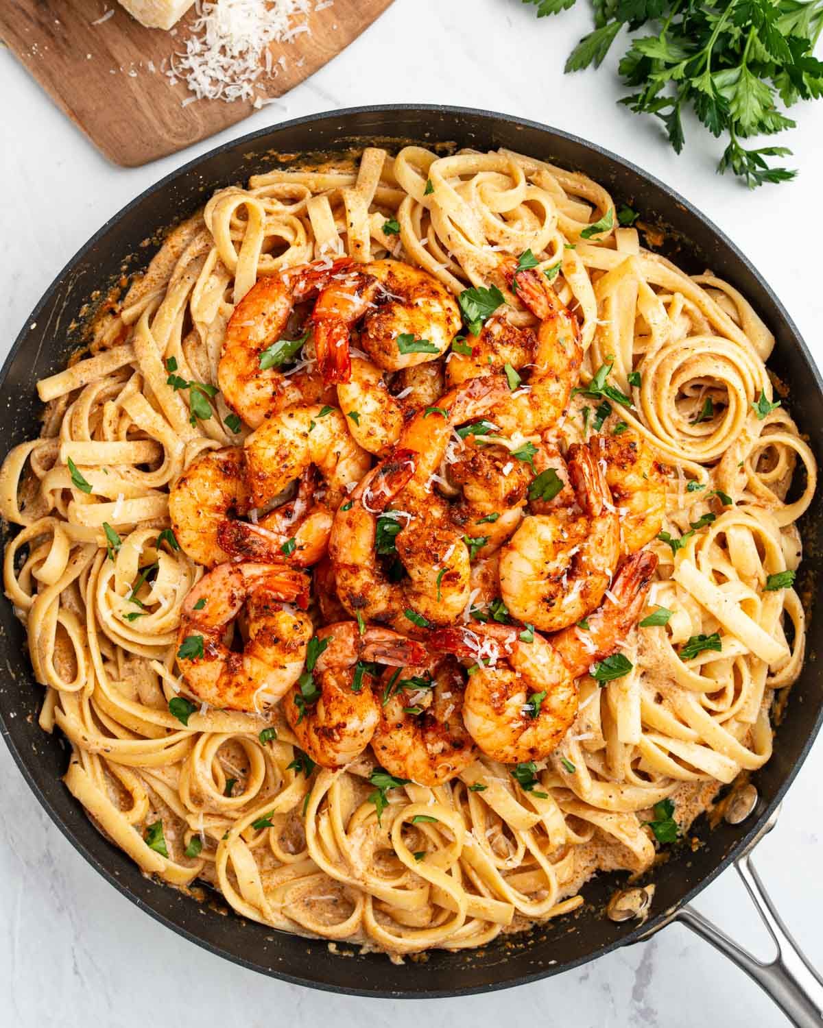 A large saute pan with pasta and cajun shrimp.