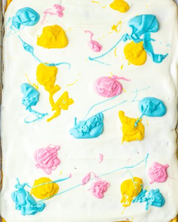 A baking tray with vanilla almond bark with colored candy melts to make saltine toffee for Easter.