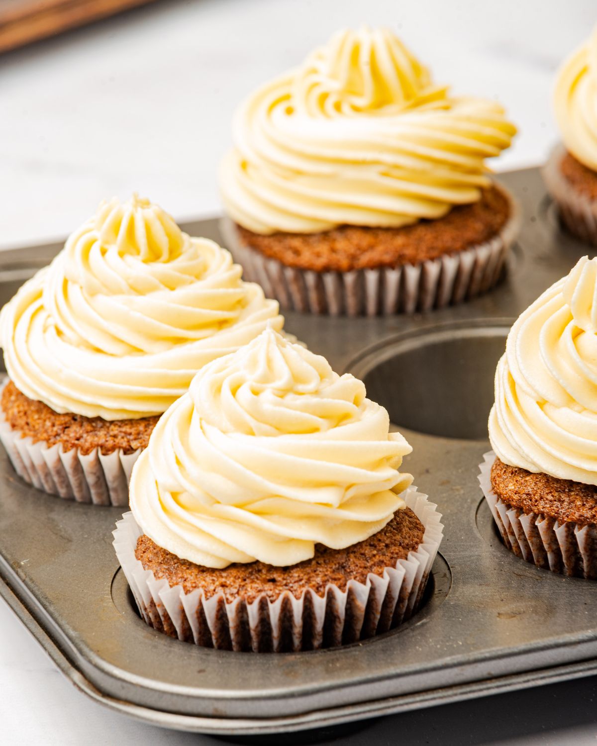 Cupcakes in a muffin tin topped with Irish cream butterbream frosting.