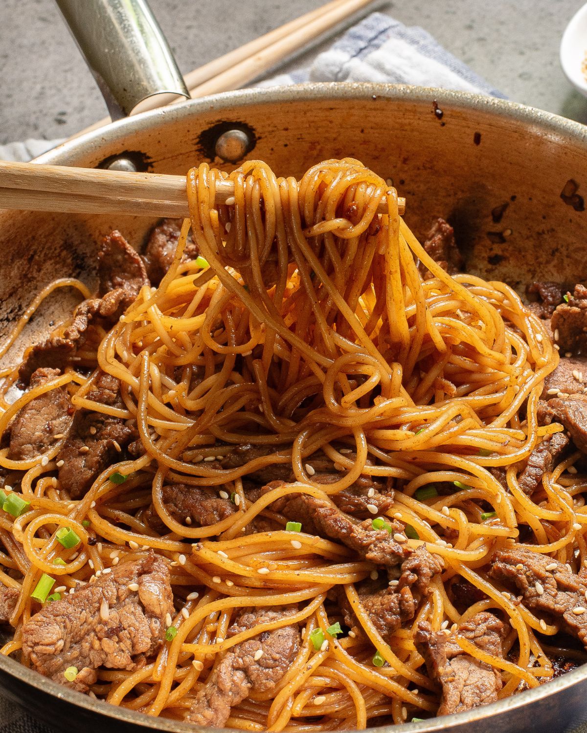 A saute pan with noodles Asian noodles and steak with hibachi seasonings.