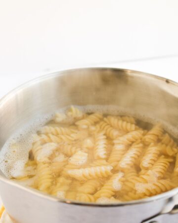 Rotini pasta being cooked to make chicken caesar pasta salad.