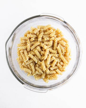 Rotini pasta in a bowl ready to make chicken caesar pasta salad.
