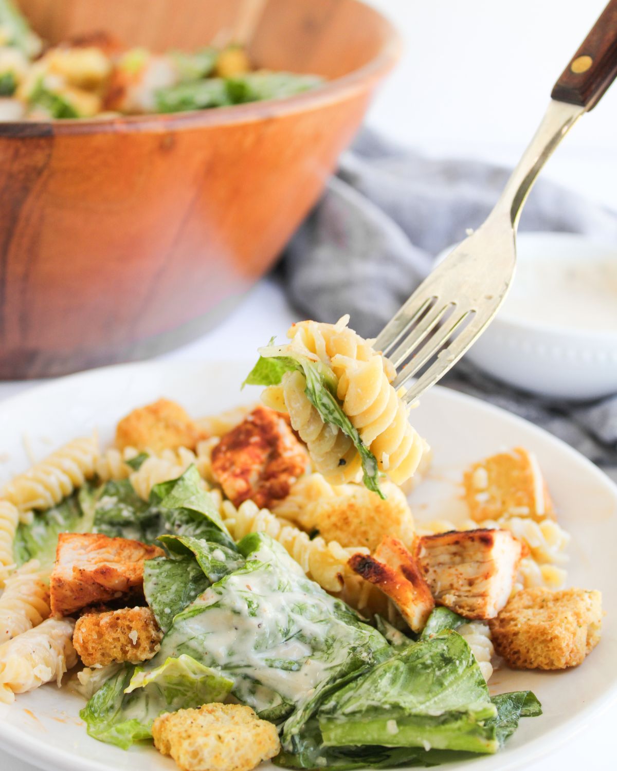 Creamy chicken caesar pasta salad with lettuce on a plate with a fork in the pasta salad.