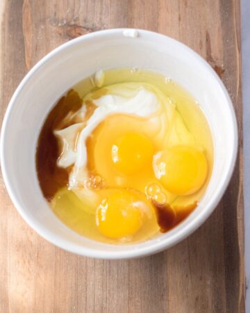 A bowl of eggs and sour cream to make a chocolate cake.