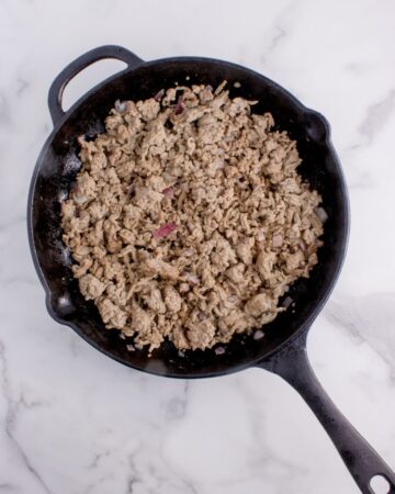 Hamburger meat browned in a cast iron skillet to make a hash brown casserole. 