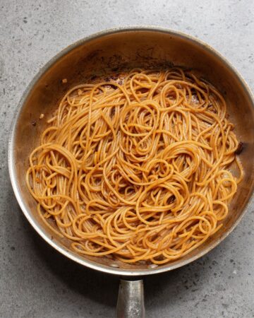 A large saute pan with cooked noodles to make hibachi noodles and steak. 