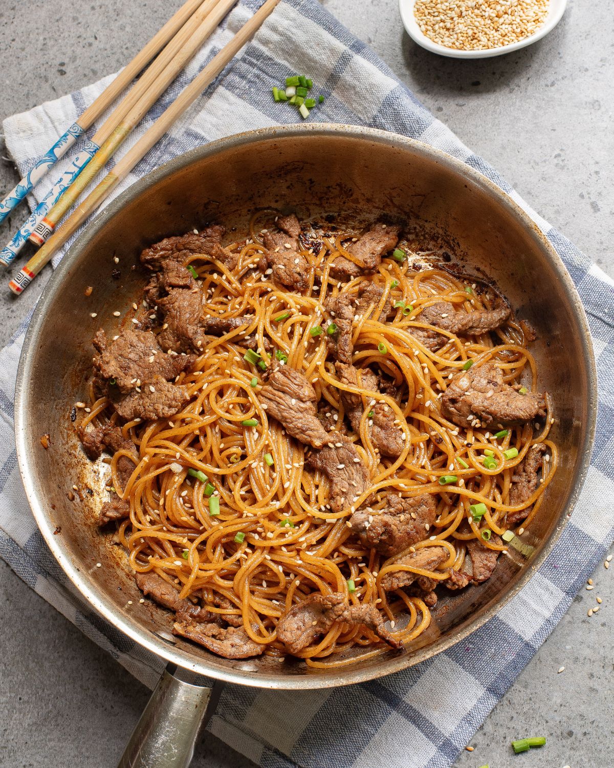Hibachi Noodles and steak with sesame seeds in a saute pan. 