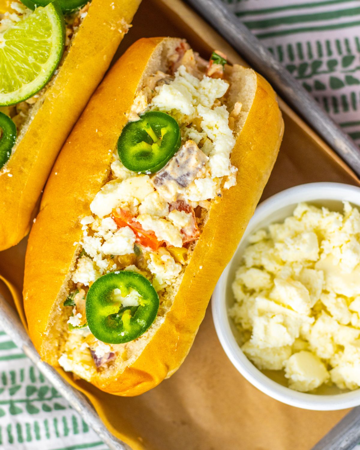 Mexican street corn chicken salad in a roll topped with sliced jalapenos.