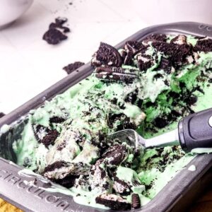 Mint Oreo no churn ice cream in a pan being scooped out of the pan.