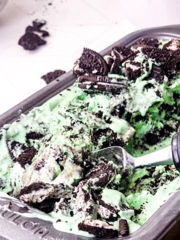 Mint Oreo no churn ice cream in a pan being scooped out of the pan.