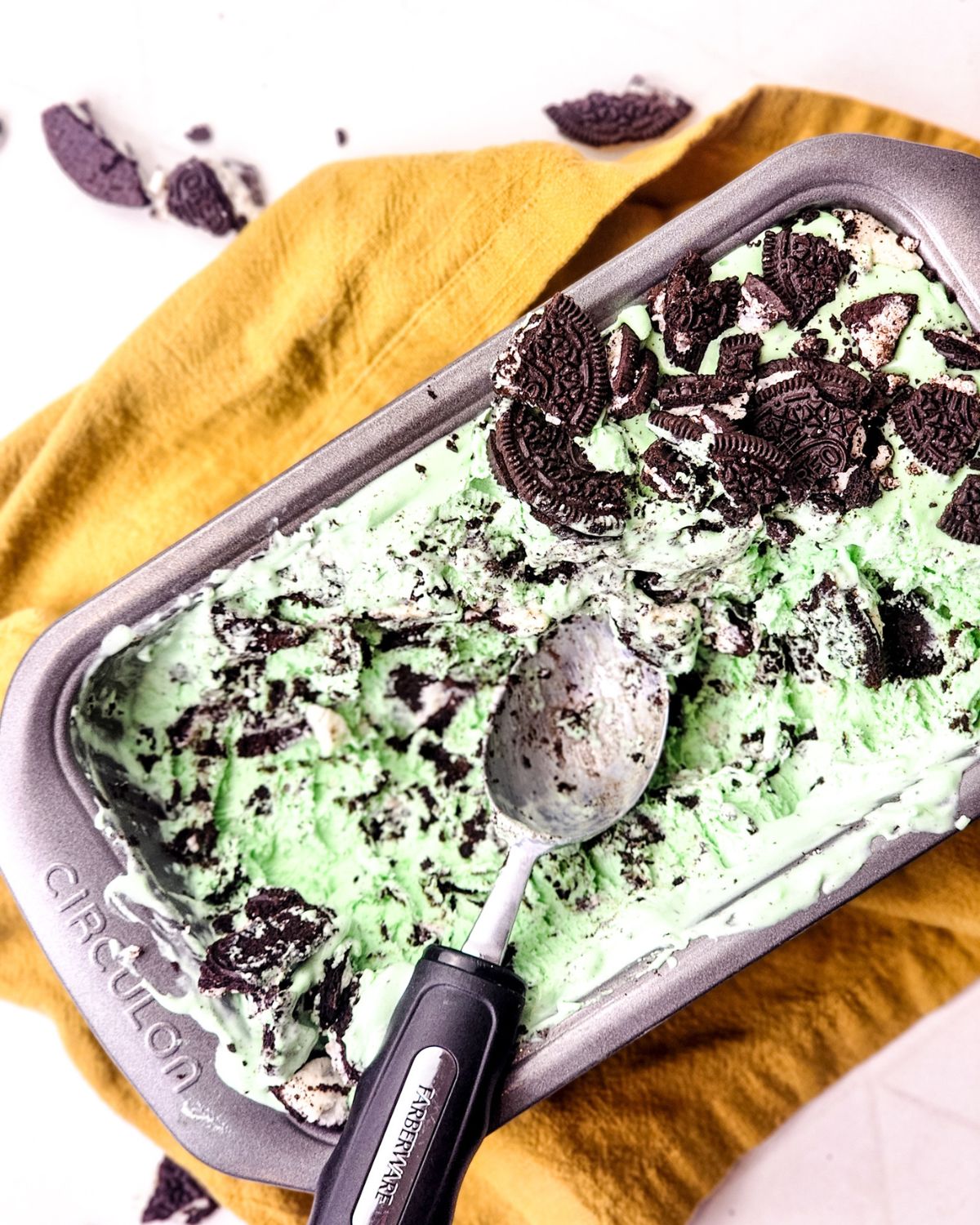 A loaf pan with homemade mint Oreo ice cream with a scoop in the pan.