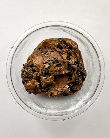 A glass mixing bowl with the ingredients to make oreo s'mores cookies. 
