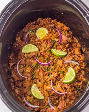 Slow cooker with cooked beef stew meat shredded to make birria sliders. 
