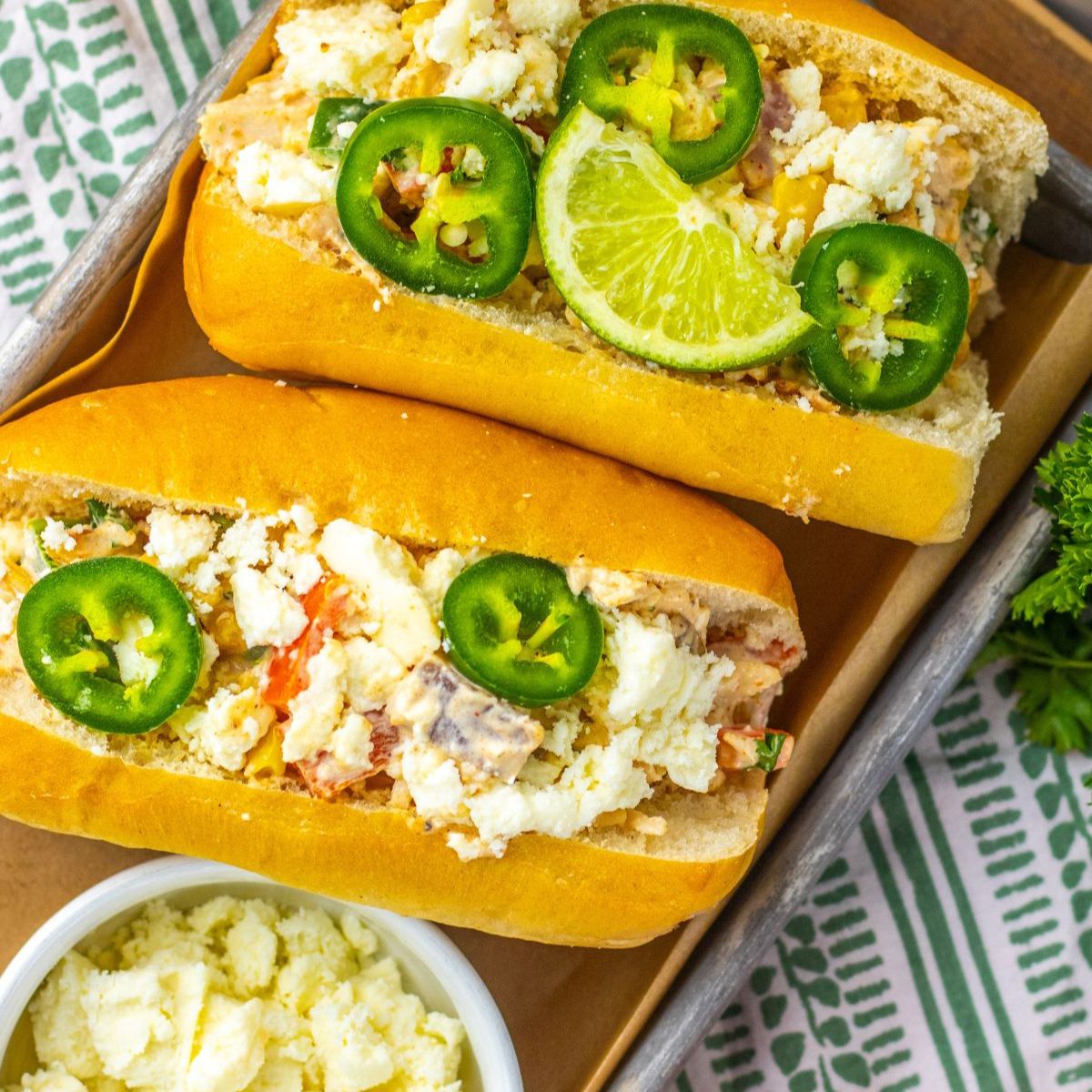 Mexican chicken salad in rolls topped with jalapeno and sliced limes.