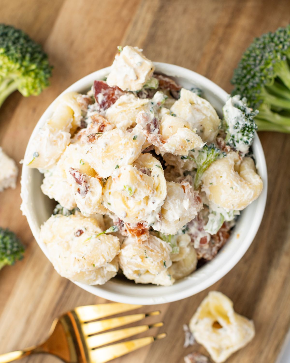 A white bowl with tortellini salad with ranch, bacon, and broccoli.
