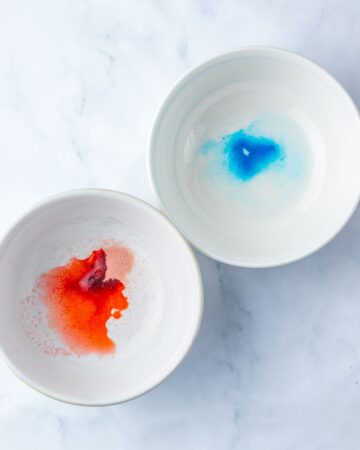 Two bowls with red and blue gelatin to make cookies.