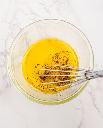 A glass bowl with the ingredients to make a dressing for a corn tomato salad.