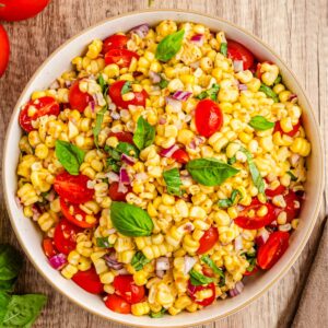 A corn tomato salad in a bowl on a wooden surface.