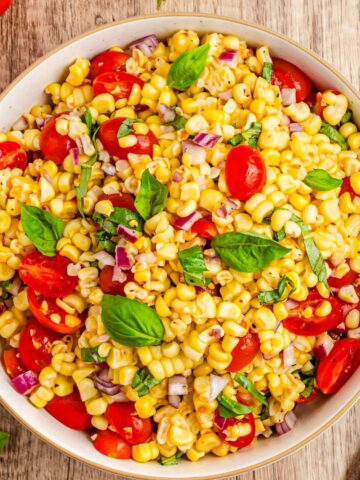 A corn tomato salad in a bowl on a wooden surface.