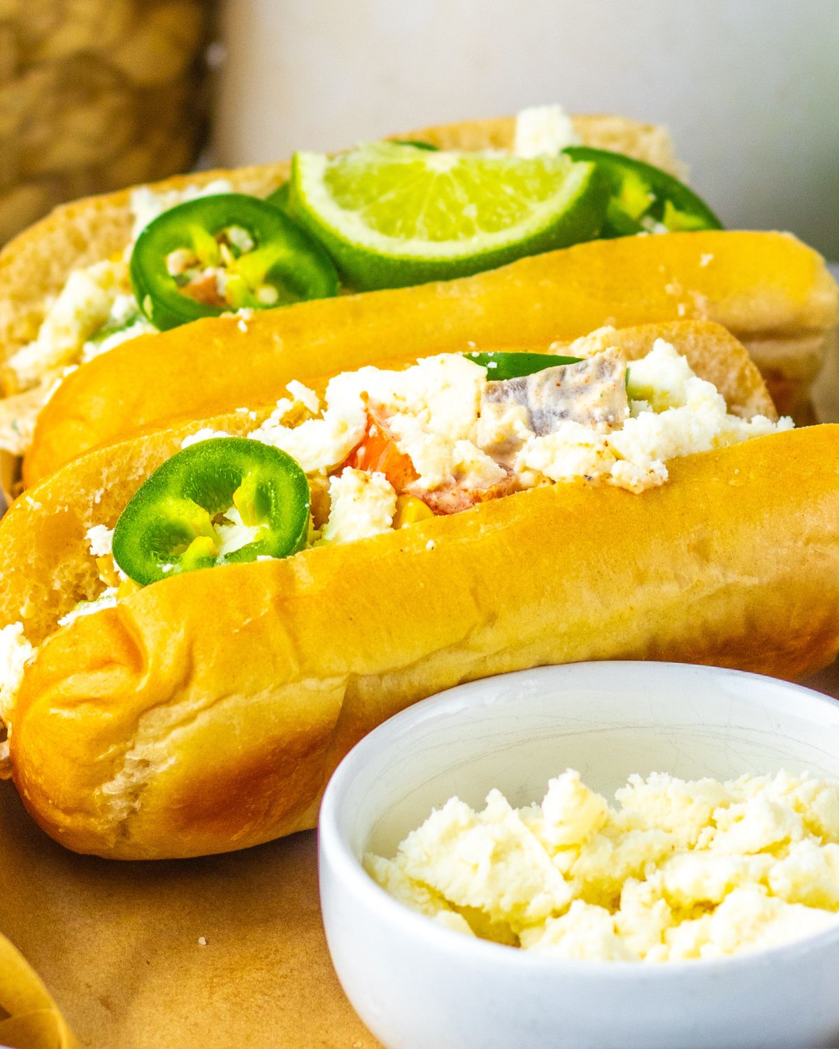 Hoagie Buns filled with Street Corn Mexican Chicken salad topped with jalapenos and lime wedges.