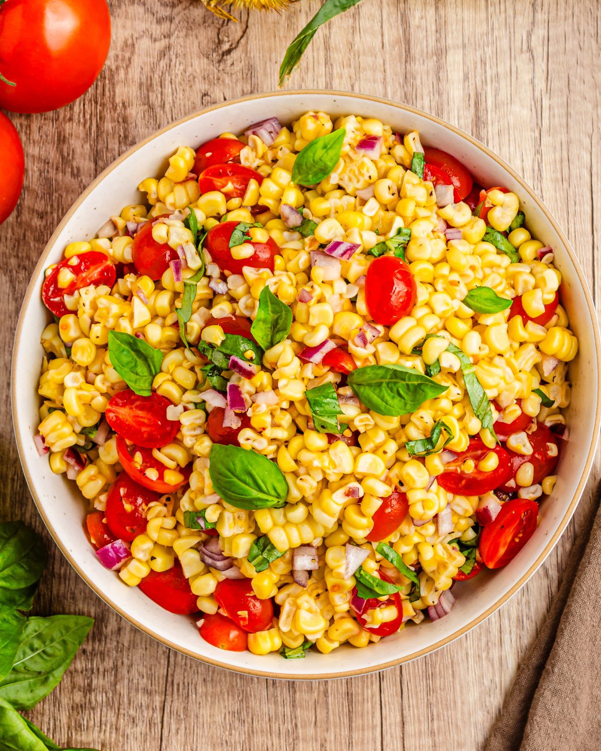 A fresh corn and tomato salad with basil with a lemon dressing in a bowl. 