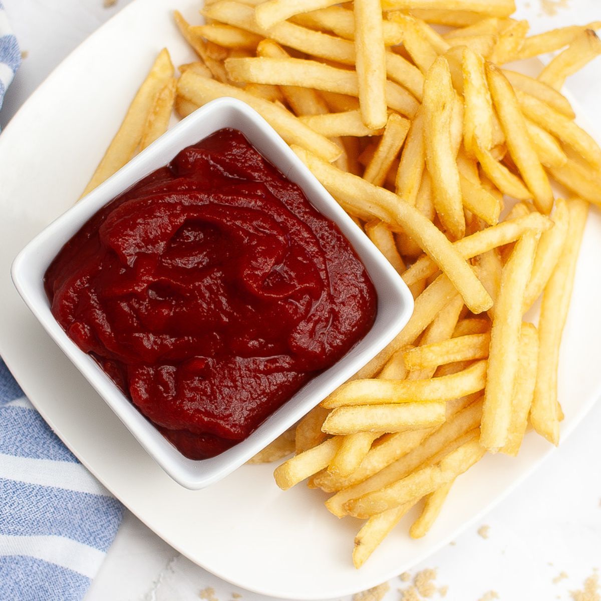 An overhead view of homemade ketchup in a bowl with french fries on the side.