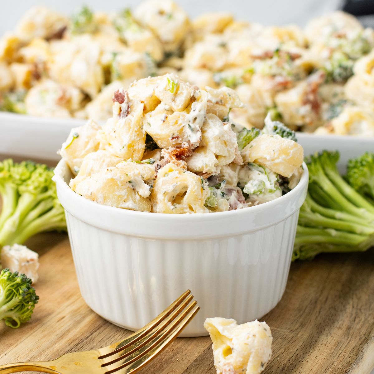 A white bowl with bacon ranch tortellini salad in a bowl on a wooden board.
