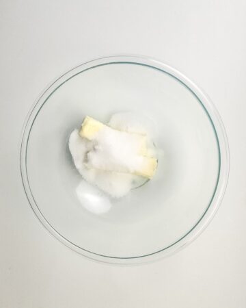 A glass bowl with butter and sugar to make millionaire brownies.