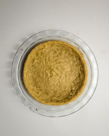 A sugar cookie base in a glass pie plate for a fruit pizza.