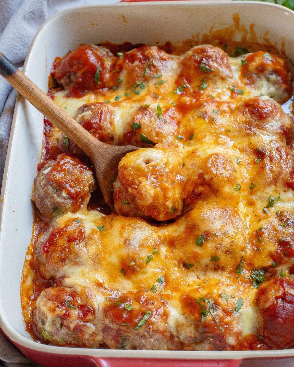 A Mexican enchilada meatball casserole with meatballs topped with enchilada sauce and melted shredded jack cheese.