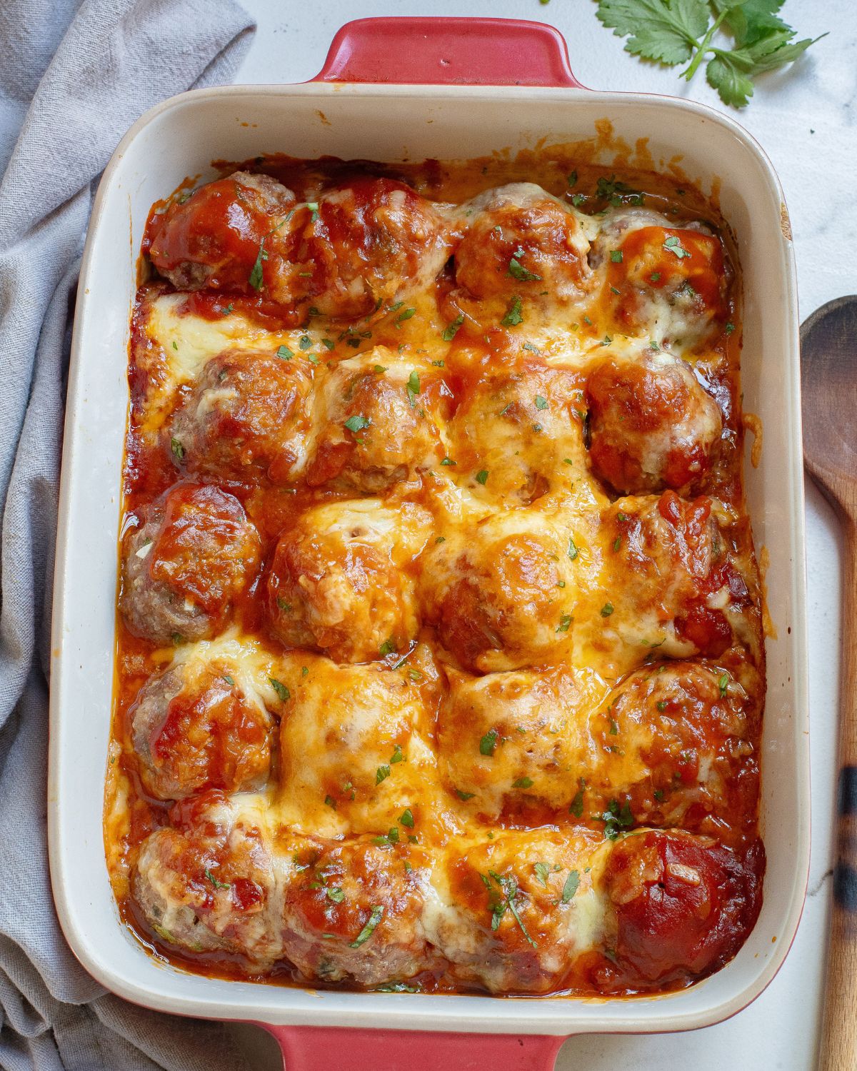 A large casserole dish with enchilada meatballs tppped with enchilada sauce and melted jack cheese.