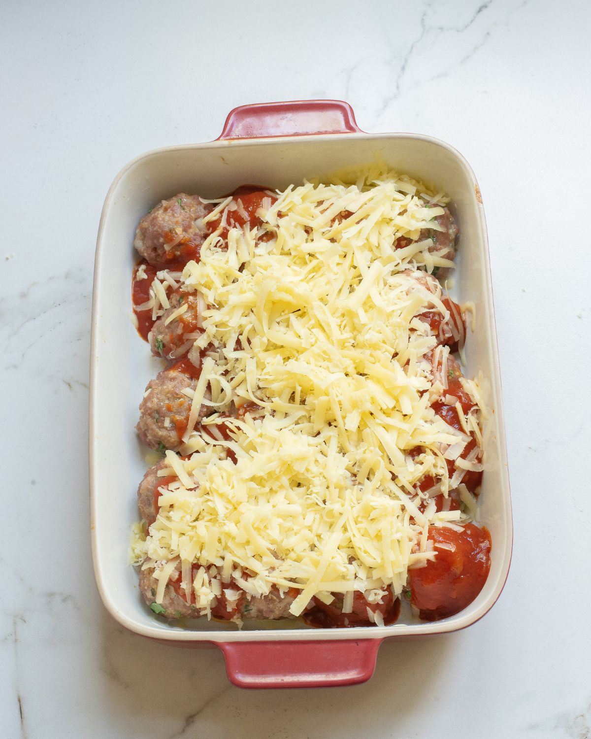 Enchilada meatballs topped with enchilada sauce and topped with shredded jack cheese.