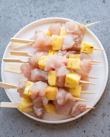 Wooden skewers with diced chicken and pineapple cubes on the skewers