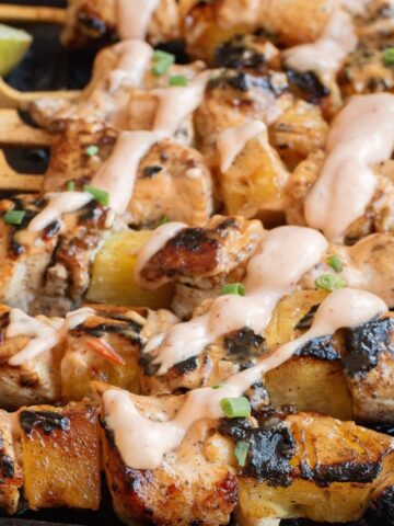 Bang Bang chicken skewers with bang bang sauce drizzled on the chicken and pineapple chunks.