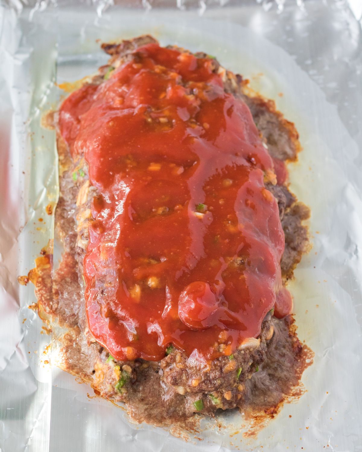 A process photo of cracker barrel meatloaf topped with a ketchup glaze.