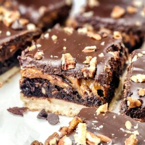 A shortbread crust brownie with a chocolate ganache topping with pecans on a platter.