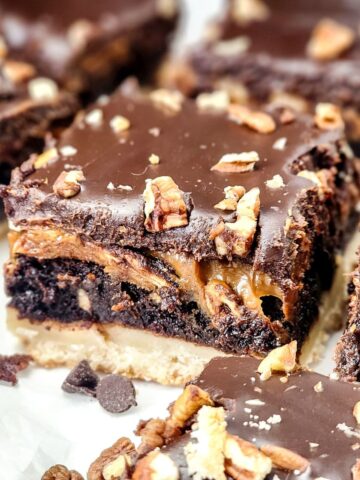 A shortbread crust brownie with a chocolate ganache topping with pecans on a platter.