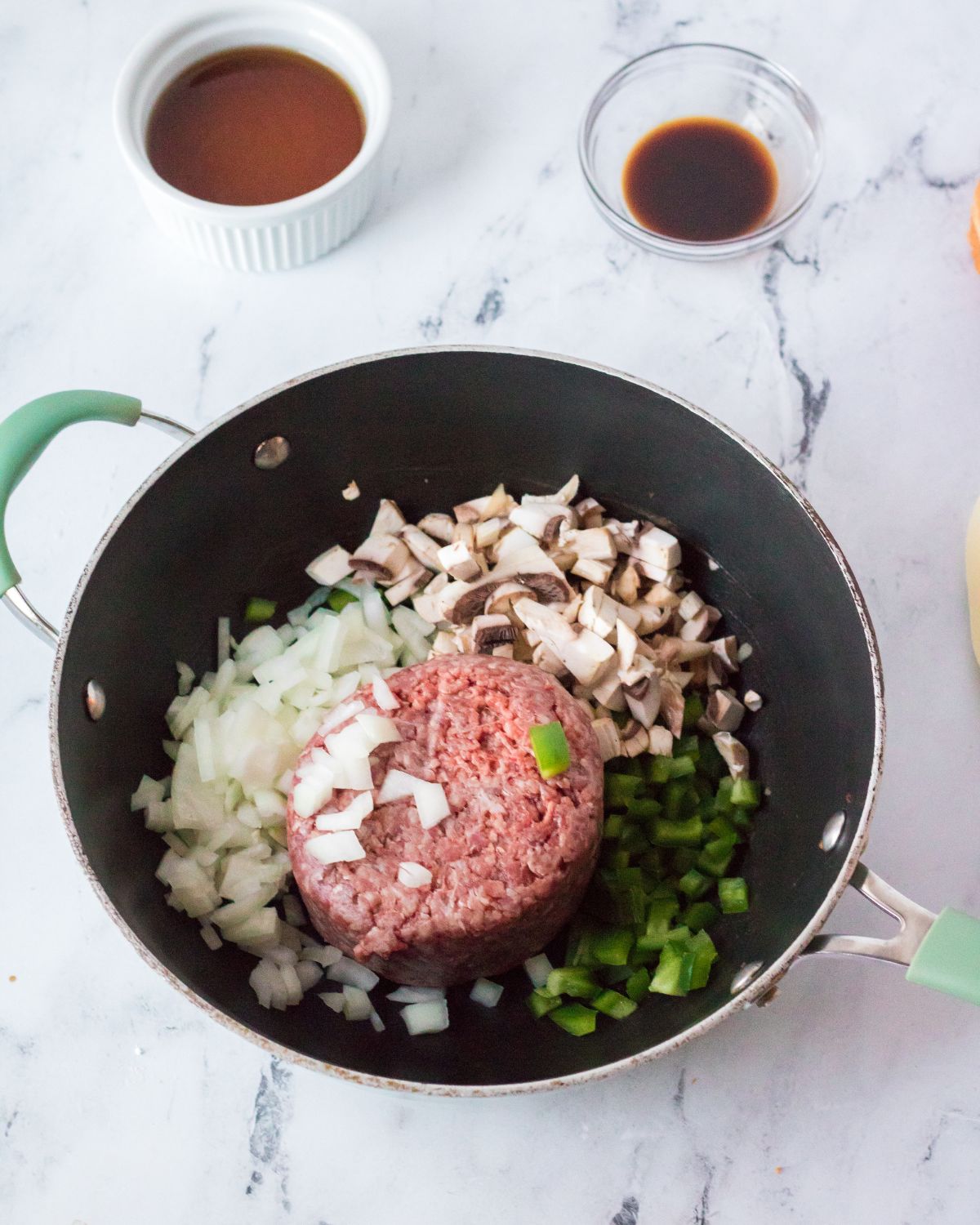 A large pan with ground beef, mushrooms, onions and green peppers to make a slow cooker philly cheesecake sloppy joes. Browning the ingredients.