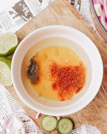 A white bowl with the ingredients to make a vinaigrette for a watermelon feta cucumber salad.