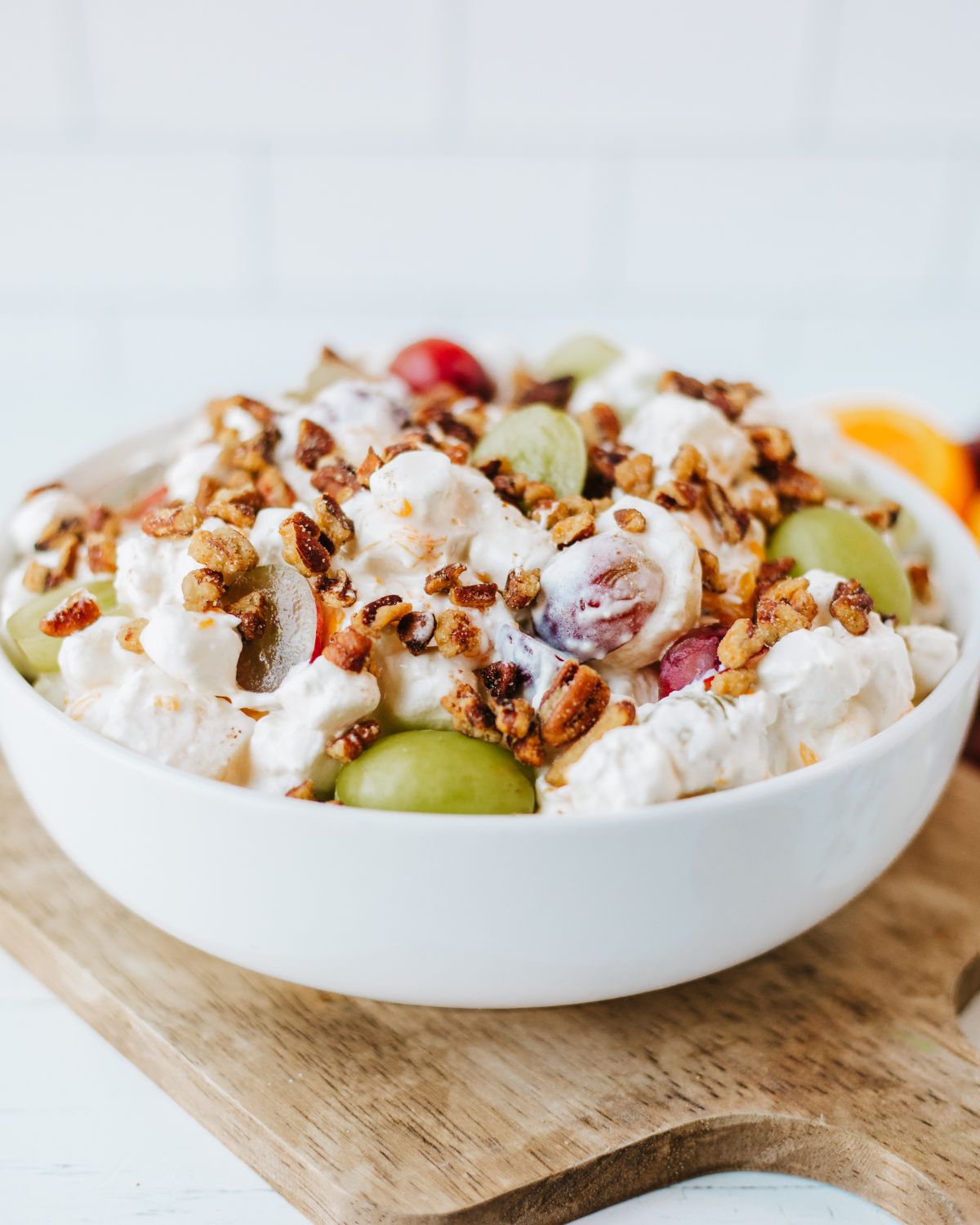 A white bowl of grapes and pecans in a creamy dressing.