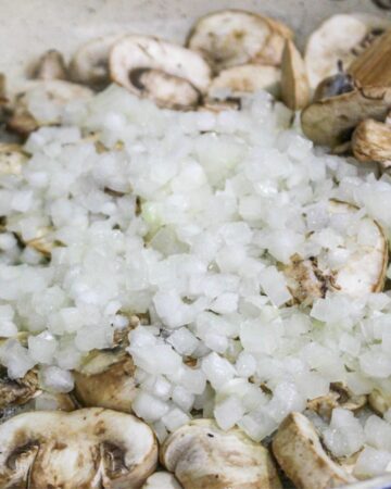 Mushrooms and onions being sauteed to make a green bean chicken casserole.