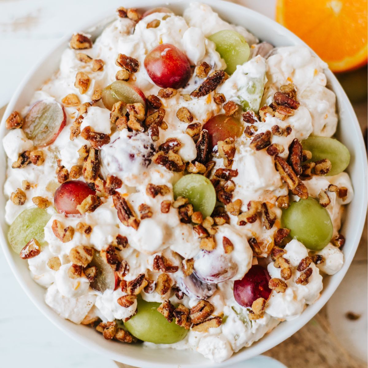 An overhead view of a classic grape salad in a creamy dressing with pecans on top.